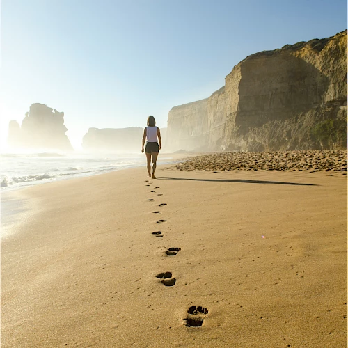 femme marchant seule sur le sable laissant des traces de pas sur le sable